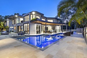 Pool in front of two storey house lit up in early evening